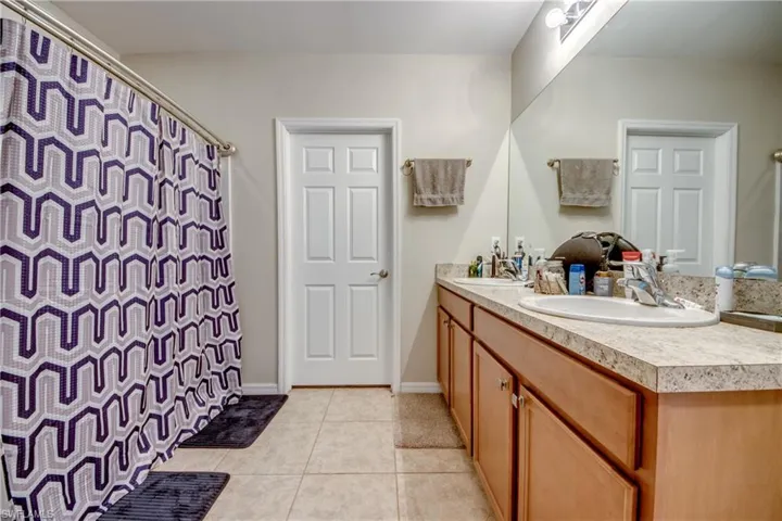 Bathroom with double vanity, tile patterned flooring, and curtained shower
