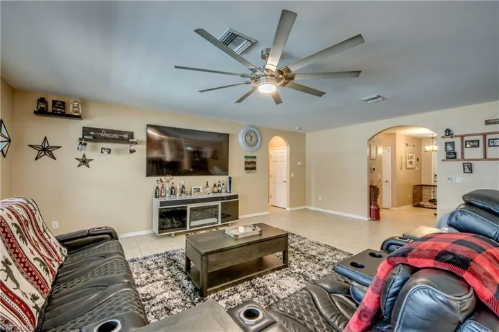 Tiled living area featuring arched walkways and a ceiling fan