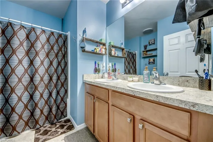 Full bath featuring double vanity, a shower with shower curtain, and tile patterned flooring