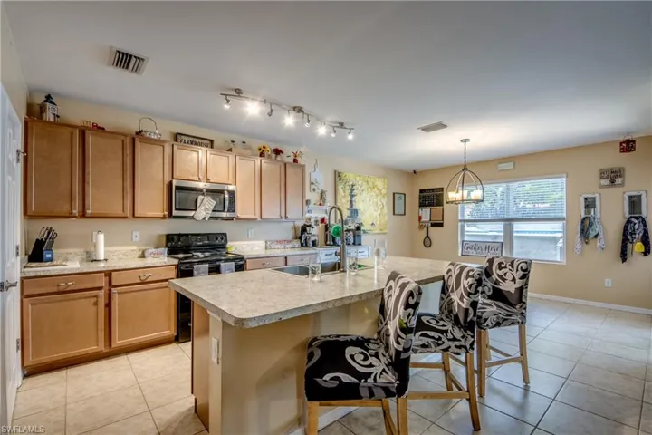 Kitchen featuring stainless steel microwave, electric range, light countertops, and light tile patterned floors