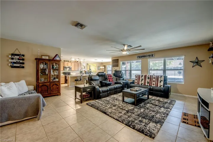 Living area with a ceiling fan, a chandelier, and light tile patterned floors