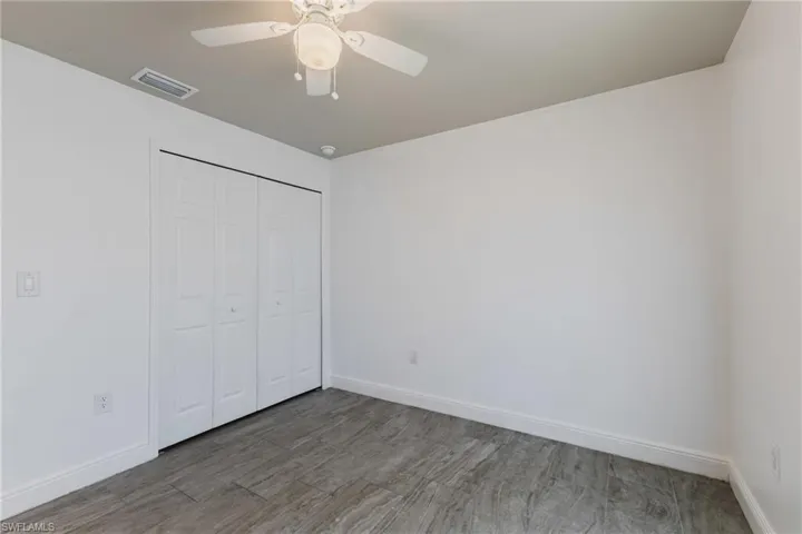 Unfurnished bedroom featuring a closet, wood finished floors, and ceiling fan