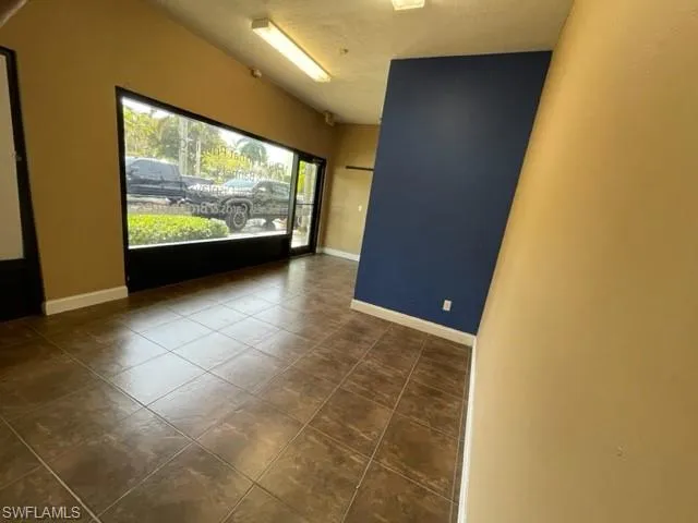 Spare room with baseboards and dark tile patterned flooring