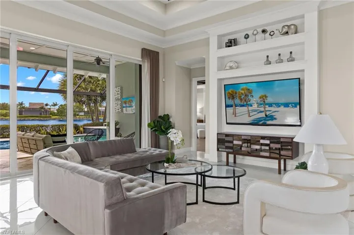 Tiled living room with a water view, crown molding, and built in shelves
