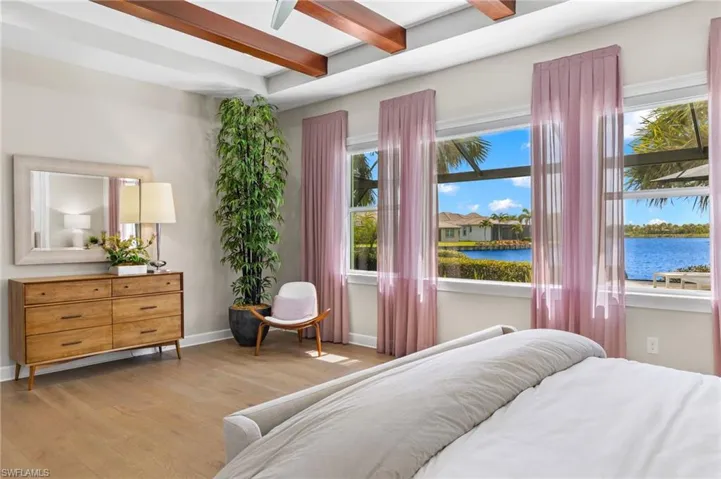 Bedroom featuring multiple windows, a water view, beam ceiling, and hardwood / wood-style floors