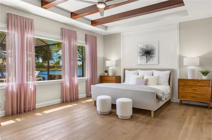 Bedroom featuring ceiling fan, a water view, light wood-type flooring, beam ceiling, and a tray ceiling