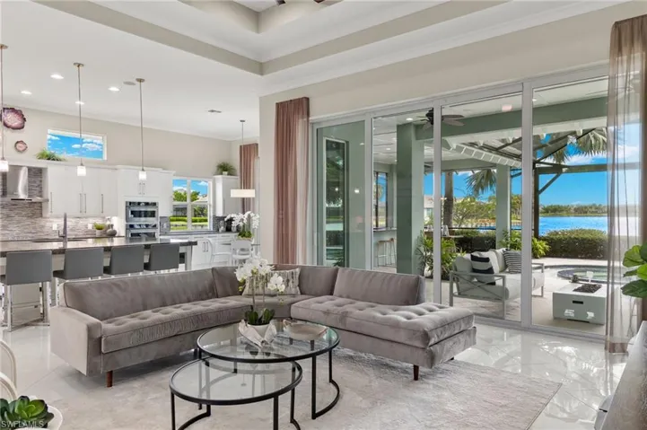 Living room featuring sink, a water view, crown molding, and light tile patterned floors