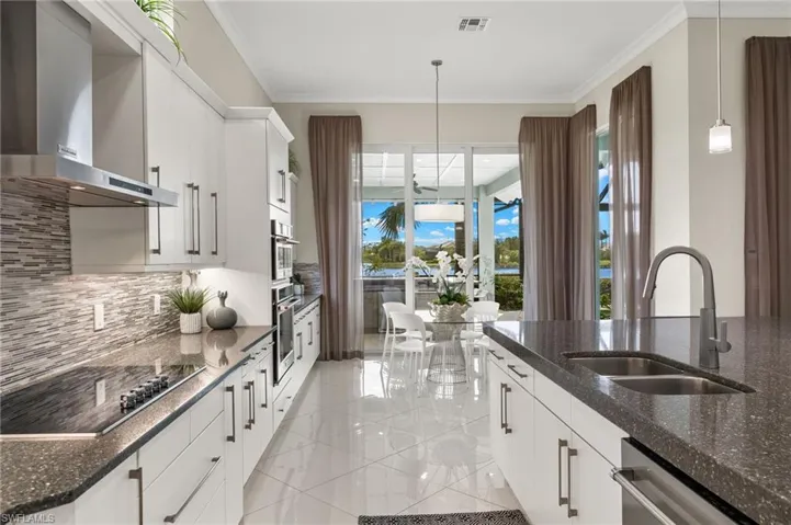 Kitchen featuring white cabinets, appliances with stainless steel finishes, wall chimney exhaust hood, sink, and plenty of natural light