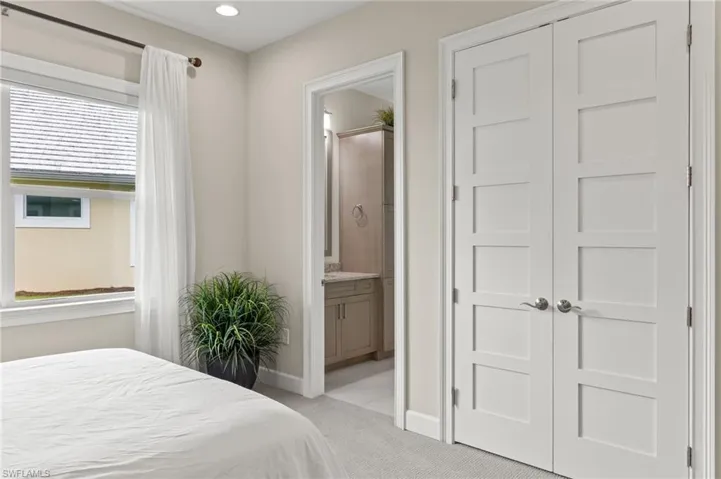 Bedroom featuring ensuite bathroom, multiple windows, light carpet, and a closet