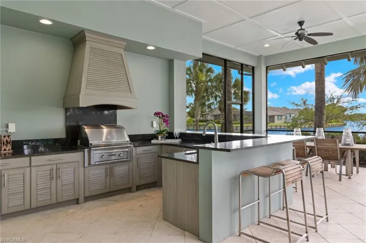 Kitchen featuring dark stone countertops, light tile patterned floors, backsplash, premium range hood, and ceiling fan