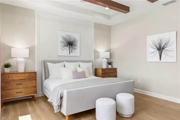 Bedroom with light hardwood / wood-style floors and beam ceiling