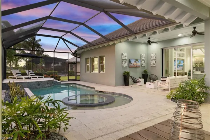 View of swimming pool with an in ground hot tub, glass enclosure, a patio area, and ceiling fan