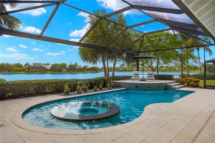 View of pool with an in ground hot tub, a water view, a patio, and a lanai