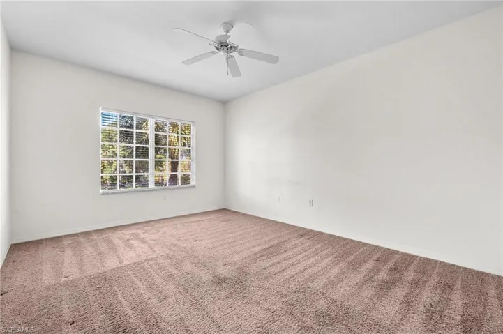 Carpeted spare room with a ceiling fan and baseboards