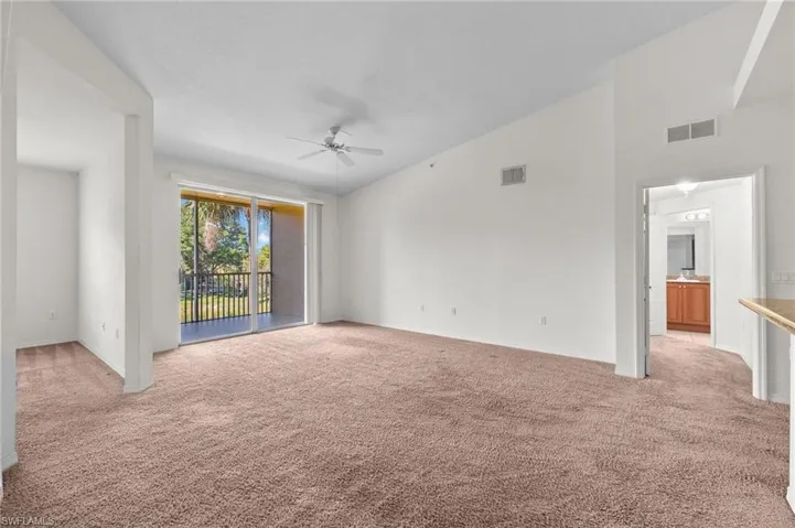 Carpeted spare room with lofted ceiling and ceiling fan