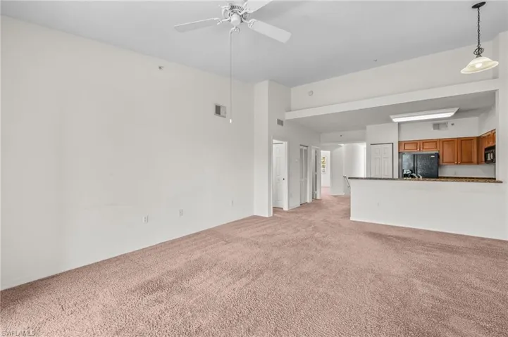 Unfurnished living room featuring light colored carpet and a ceiling fan