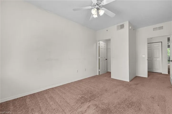 Unfurnished bedroom with carpet, a spacious closet, and ceiling fan