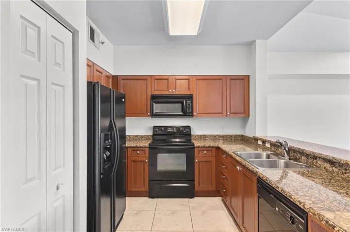 Kitchen featuring black appliances, brown cabinets, and dark stone counters