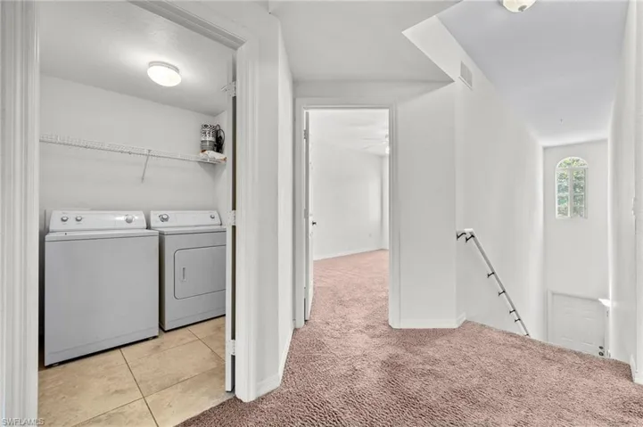 Laundry room with light carpet, light tile patterned floors, and separate washer and dryer