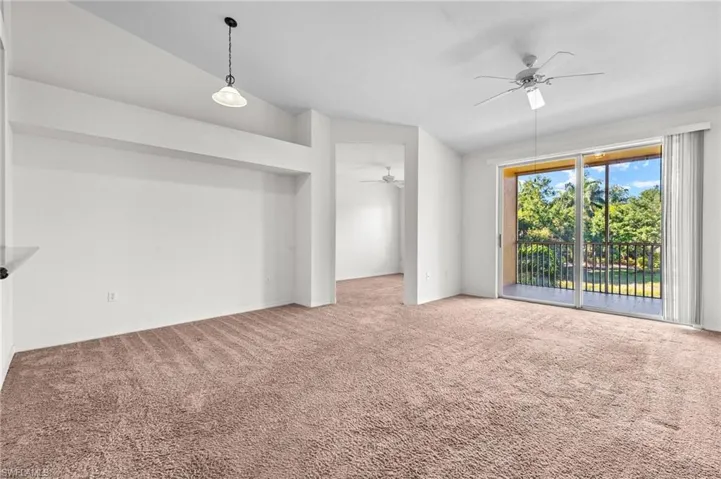 Unfurnished living room featuring vaulted ceiling, carpet floors, and ceiling fan