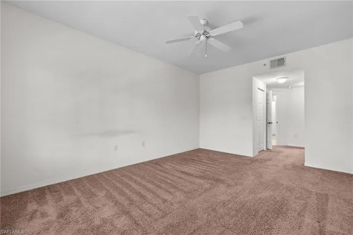 Carpeted spare room with a ceiling fan and baseboards