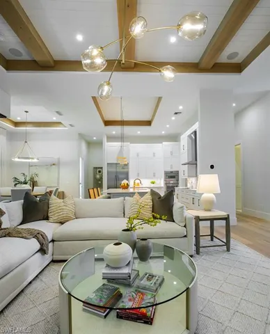 Living room with a tray ceiling, beam ceiling, recessed lighting, and light wood-type flooring