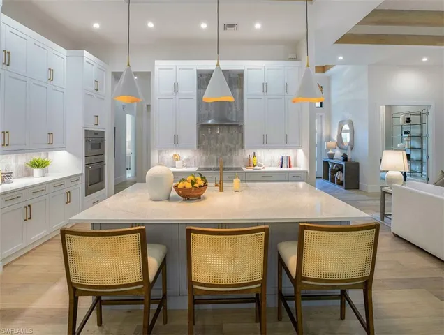 Kitchen with pendant lighting, light wood-style flooring, recessed lighting, light stone counters, and open floor plan