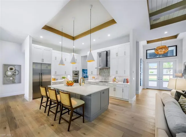 Kitchen featuring open floor plan, a breakfast bar, french doors, appliances with stainless steel finishes, and white cabinets