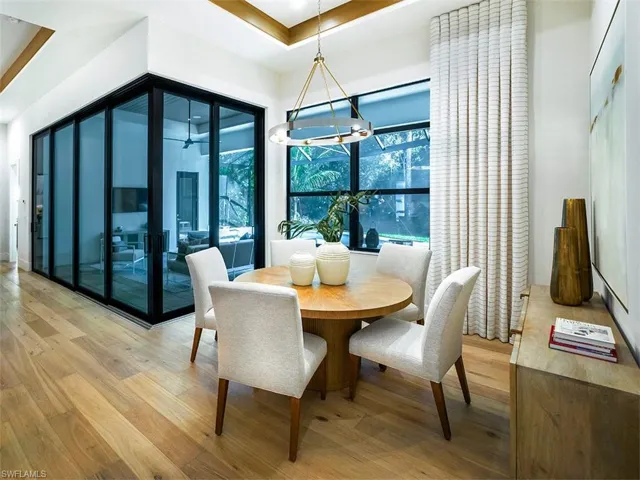 Dining room with light wood-style flooring, a tray ceiling, and a chandelier