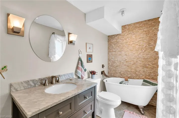 Bathroom featuring vanity, a tub to relax in, tile patterned floors, and toilet