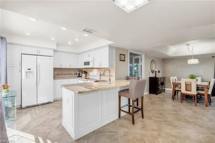 Kitchen with white cabinetry, kitchen peninsula, white appliances, and decorative light fixtures