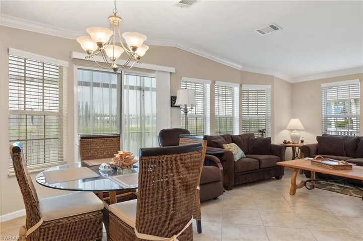 Tiled dining area featuring crown molding, plenty of natural light, and a chandelier