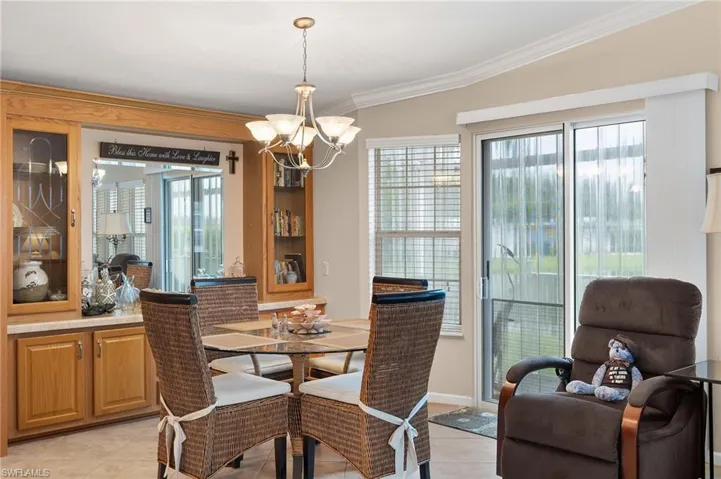 Tiled dining area with lofted ceiling, crown molding, an inviting chandelier, and a healthy amount of sunlight