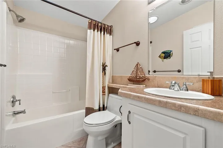 Full bathroom featuring vanity, tile patterned floors, toilet, and shower / tub combo with curtain