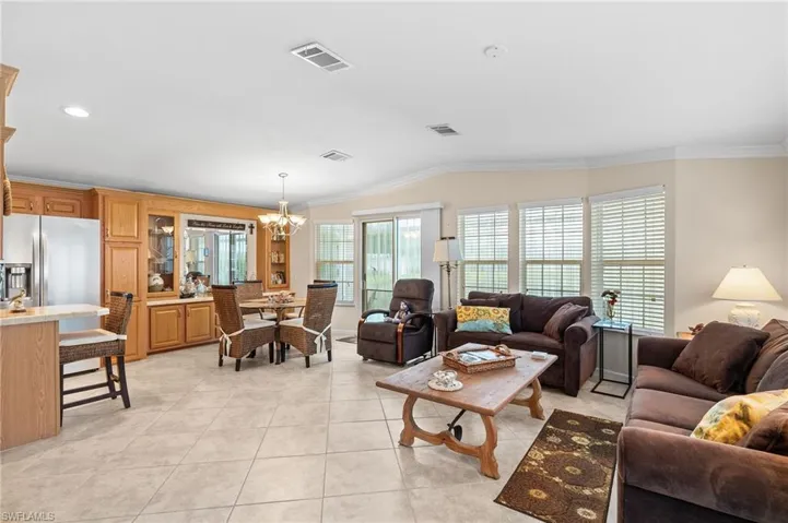 Living room featuring light tile patterned floors, crown molding, vaulted ceiling, and an inviting chandelier
