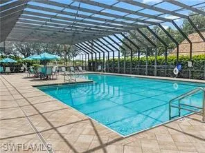 View of swimming pool with a patio and glass enclosure