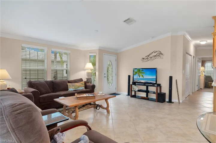 Tiled living room featuring ornamental molding and a healthy amount of sunlight