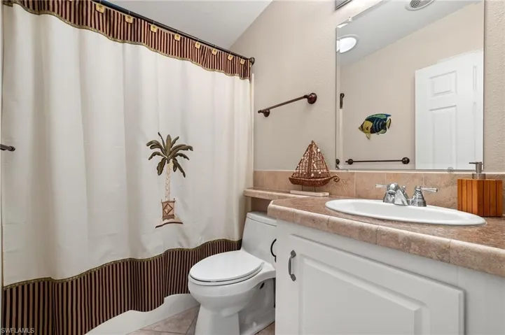 Bathroom featuring tile patterned floors, vanity, walk in shower, and toilet
