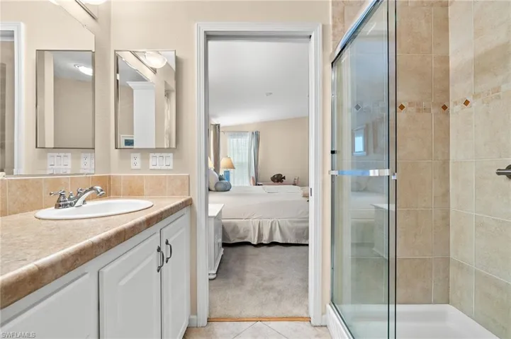Bathroom featuring lofted ceiling, tile patterned flooring, a shower with door, and vanity