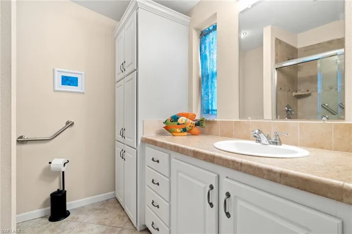 Bathroom with vanity, backsplash, a shower with door, and tile patterned floors