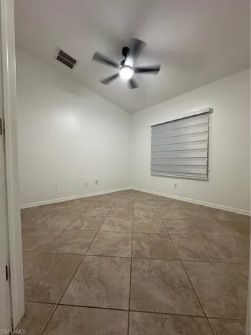 Empty room with ceiling fan and light tile patterned floors