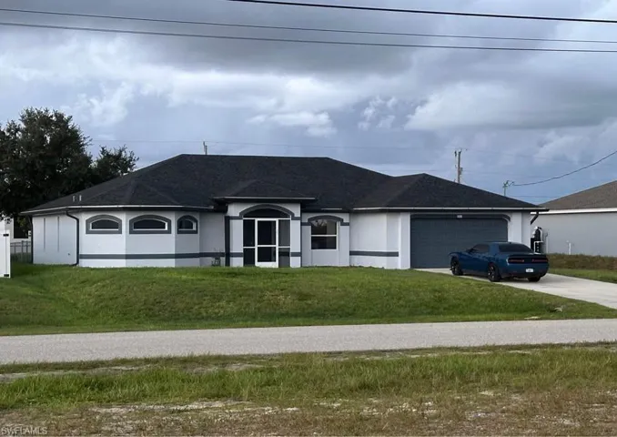 Single story home with a front lawn, stucco siding, concrete driveway, an attached garage, and a shingled roof