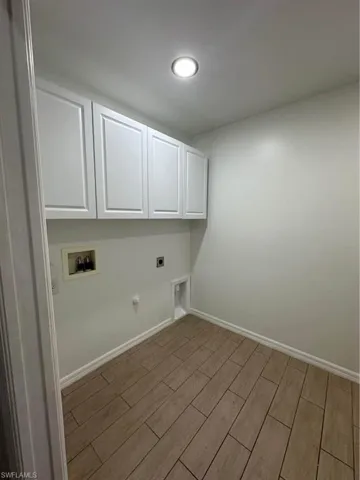 Washroom with wood tiled floors, hookup for an electric dryer, hookup for a washing machine, cabinet space, and hookup for a gas dryer