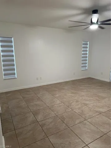 Empty room with ceiling fan and light tile patterned flooring