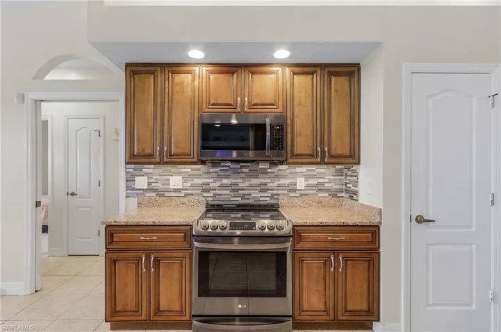 Kitchen featuring light tile patterned flooring, a breakfast bar, kitchen peninsula, ceiling fan, and appliances with stainless steel finishes