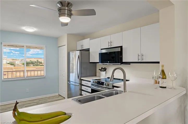 Kitchen featuring ceiling fan, white cabinets, light hardwood / wood-style floors, and appliances with stainless steel finishes