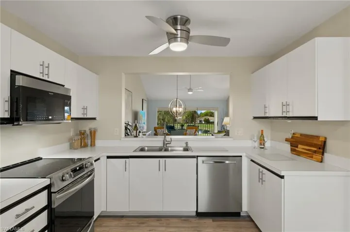 Kitchen featuring pendant lighting, stainless steel appliances, white cabinetry, and sink