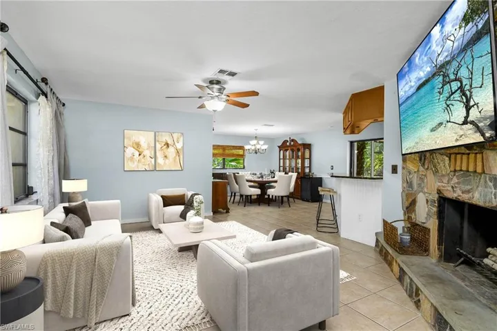 Living area with a  light tile patterned floors, a ceiling fan, and a stone fireplace