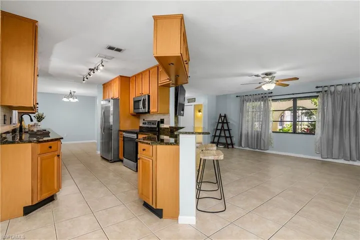 Kitchen featuring appliances with stainless steel finishes, a breakfast bar, light tile patterned floors, and tasteful backsplash