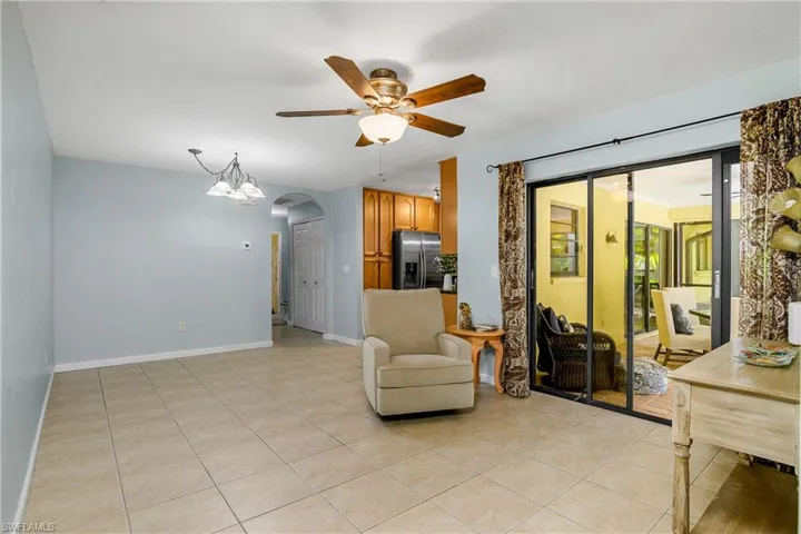 Family room area with a ceiling fan, arched walkways, and light tile patterned floors